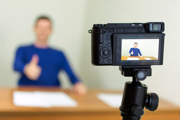 Young male blogger recording video at home using a tripod mounted digital camera