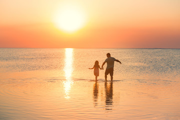 father with daughter walking by the sea