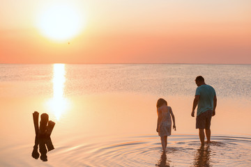 father with daughter walking by the sea