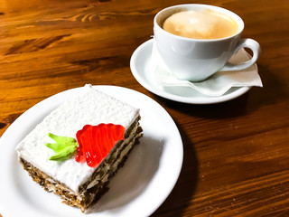 Piece of carrot cake and cappuccino on wooden table