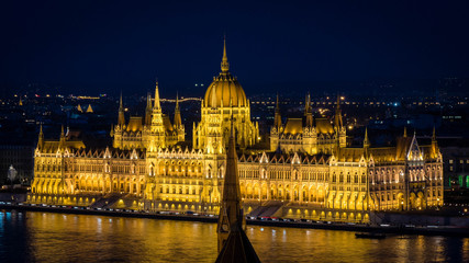 Naklejka na ściany i meble Golden Parliament of Budapest at night up close seen from opposite river bank