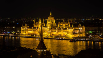 Fototapeta na wymiar Golden Parliament of Budapest at night with river Danube seen from opposite river bank