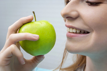 Young woman with healthy tooth biting green apple