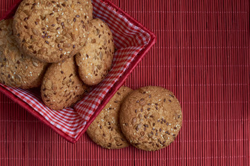 homemade oat cookies with sunflower seeds in and near red checkered basket on wooden table