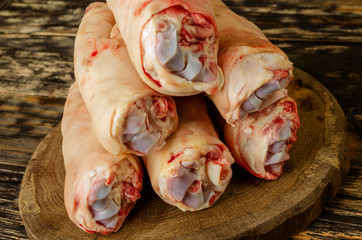 Raw and freesh pork feet or legs,over dark wooden board. They are stacked pile. Food meat shot.