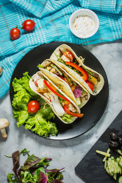 Fresh delicious mexican tacos and food ingredients on concrete rustic background