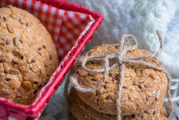 homemade oat cookies with sunflower seeds in and near red checkered basket on white and blue plaid