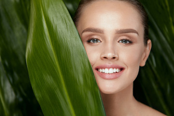 Fototapeta premium Natural Cosmetics. Beautiful Woman Face With Green Plant