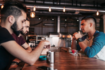 Group of mixed race young men talking and laughing in restaurant. Multiracial friends having fun in cafe. Guys hangout