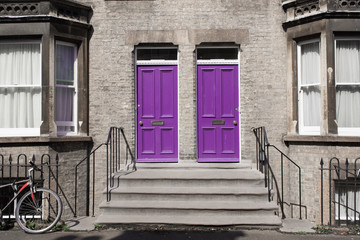 Two identical pink purple wooden front doors at the entrance of a classic Victorian british style house - 203456931