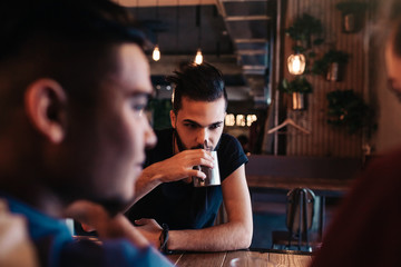 Happy arabian young men hanging in loft cafe. Friends talking in lounge bar by the window drinking tea