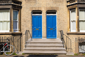 Fototapeta na wymiar Two identical blue wooden front doors at the entrance of a classic Victorian british style house