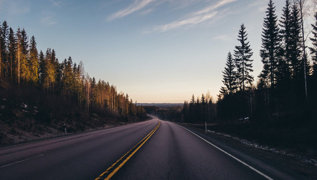 Finland road 4 E75 before Jyvaskyla, sun is rising in the horizon and the downhill makes a clear view far
