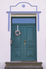 Beautiful ocean blue wooden door with easter decoration. Old house entrance.