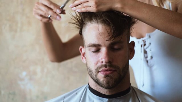 Men's haircut at the barber scissors. Great time at barbershop. Cheerful young bearded man getting haircut by hairdresser. Young Man in Barbershop Hair Care Service Concept.