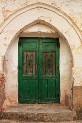 Fototapeta na wymiar Old abandoned house facade with green wooden door