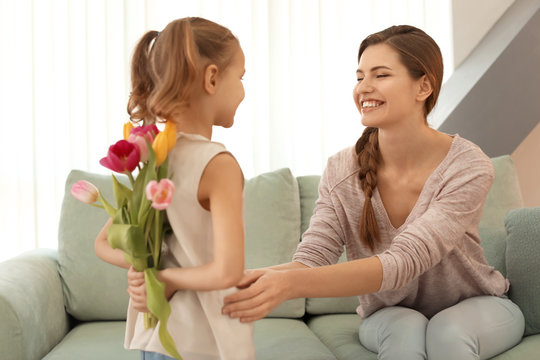 Cute little girl hiding bouquet of flowers for mother behind her back