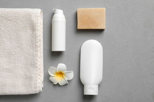 Flat lay composition with spa cosmetics and towel on grey background