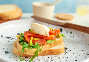 Sandwich with fresh sliced salmon fillet and avocado on plate, closeup