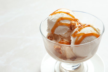 Bowl with caramel ice cream on light background