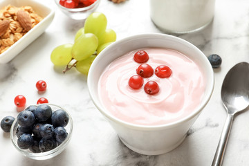 Bowl with tasty yogurt and berries on table