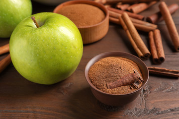 Fresh apple with cinnamon sticks and powder on wooden table