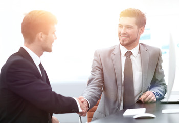 Fototapeta premium handshake of business partners sitting at a Desk.