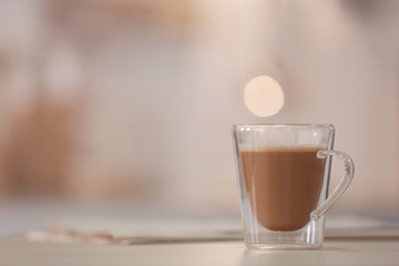 Cup of aromatic coffee on table against blurred background