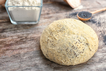 Fototapeta na wymiar Raw dough with poppy seeds on wooden table