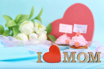 Beautiful composition with phrase I LOVE MOM, flowers, gift and cupcakes for Mother's Day on color background