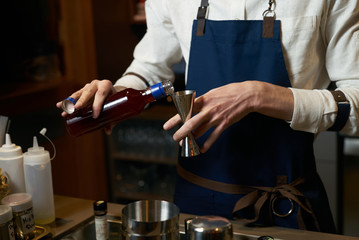 Professional bartender making a cocktail at the bar counter, close-up
