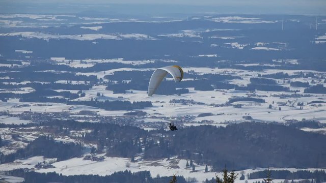 Paraglider circeling over the snow covered landscape of the Allgaeu, Germany, near Fuessen, on the northern edge of the Alps.