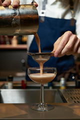 Professional bartender making a cocktail at the bar counter, close-up