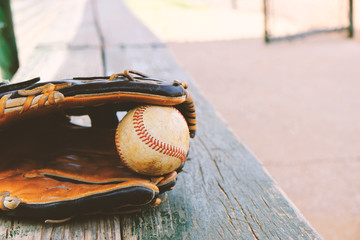 Baseball in glove laying on dugout bench before game. - obrazy, fototapety, plakaty