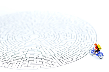 Miniature people : riding bicycle on start point of maze using as background business concept.