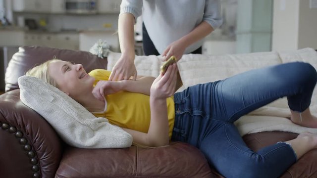 Girl climbing on sister laying on sofa and tickling her / Highland, Utah, United States