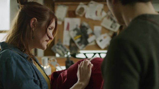 Close up of man and customer discussing red dress in workshop / Provo, Utah, United States