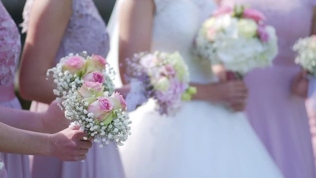 A bride and bridesmaids in pink dresses holding their bouquets.
