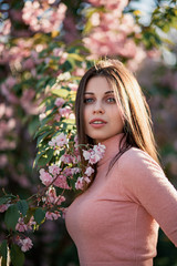 Naklejka premium a girl in a pink dress stands smiling near the cherry blossom