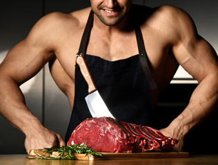 Strong sport man prepare cook beef steak ribs on dark kitchen background healthy eating concept on...