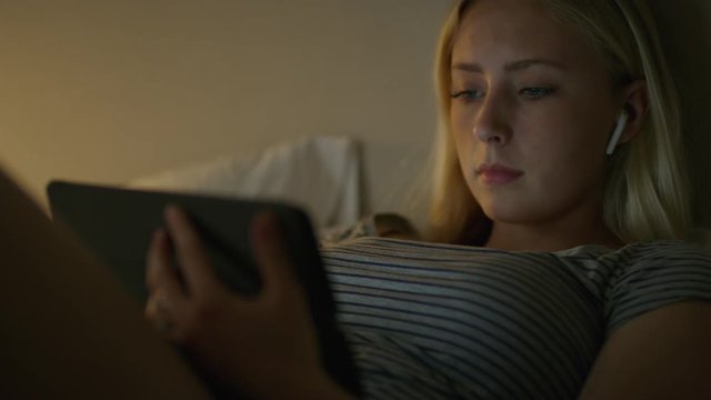 Girl laying in bed at night streaming video on digital tablet / Highland, Utah, United States