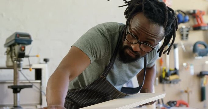 African American man carpenter measuring wooden plank 
