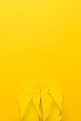 vertical image of beach flip-flops on the yellow background with copy space. summer concept