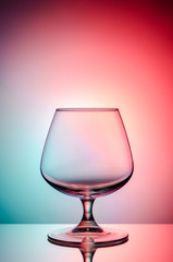 Empty glass for cognac on color, gradient background.