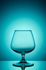 Empty glass for cognac on color, gradient background.