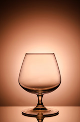Empty glass for cognac on color, gradient background.