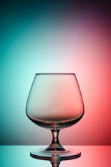 Empty glass for cognac on color, gradient background.