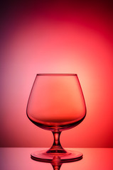 Empty glass for cognac on color, gradient background.