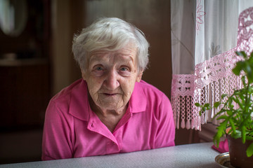Stressed elderly woman sitting at the table.