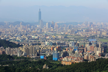 Fototapeta premium Aerial panoramic scene of overpopulated Taipei City in a hazy morning with a view of Taipei 101 tower in XinYi District, and Keelung River through the downtown area